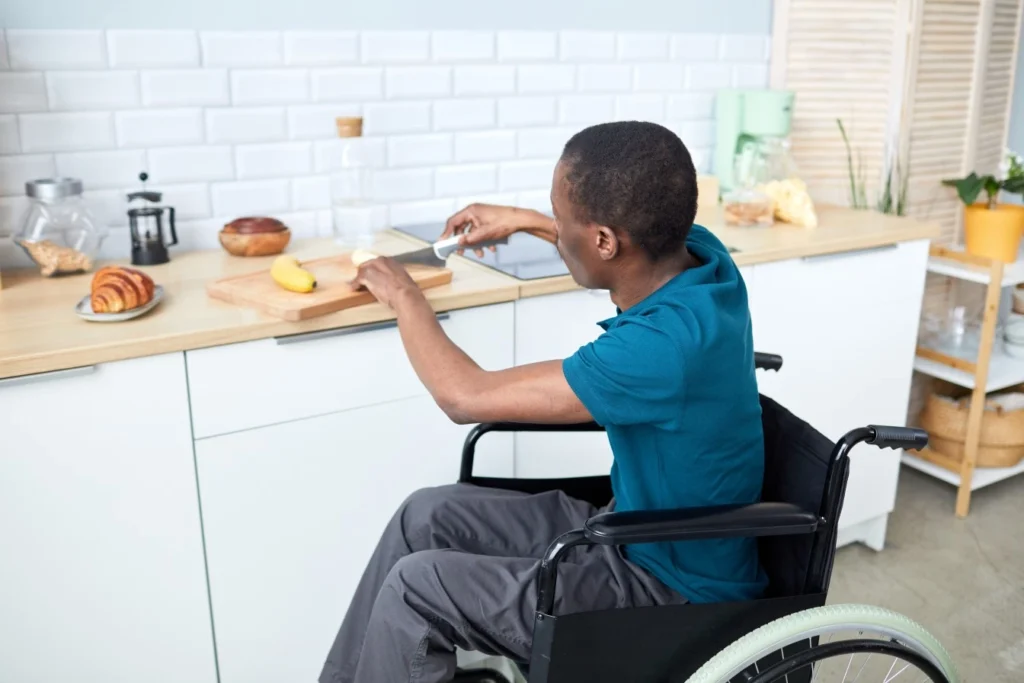 Disabled man in wheelchair chopping fruit in kitchen